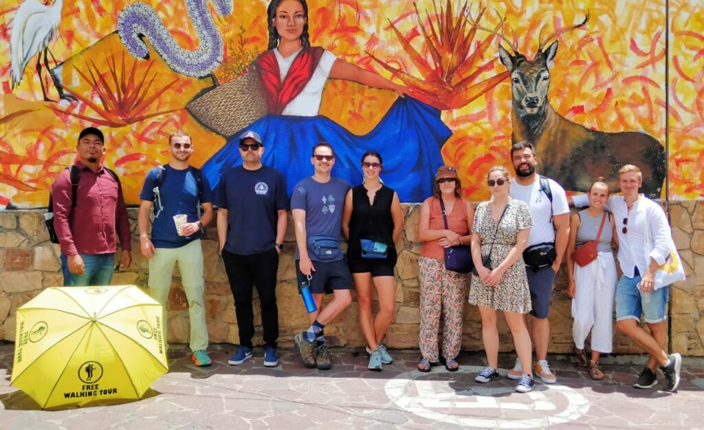 Group picture of people taking the free walking tour in Oaxaca. Standing in front of colourful wall.
