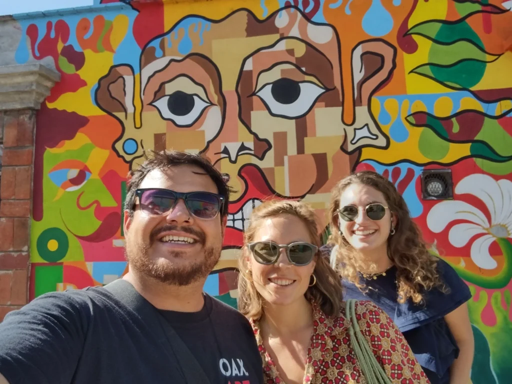 Oaxaca art walk Tour with cultura distinta. Group picture in front of colourfully painted wall.