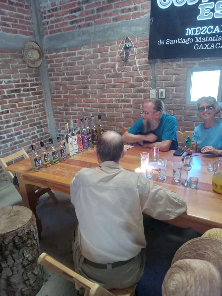 3 people at a table tasting Mezcal, in a family run business in Oacaca. This place is visited with Cultura Distintas Mezcal and hiking tour.